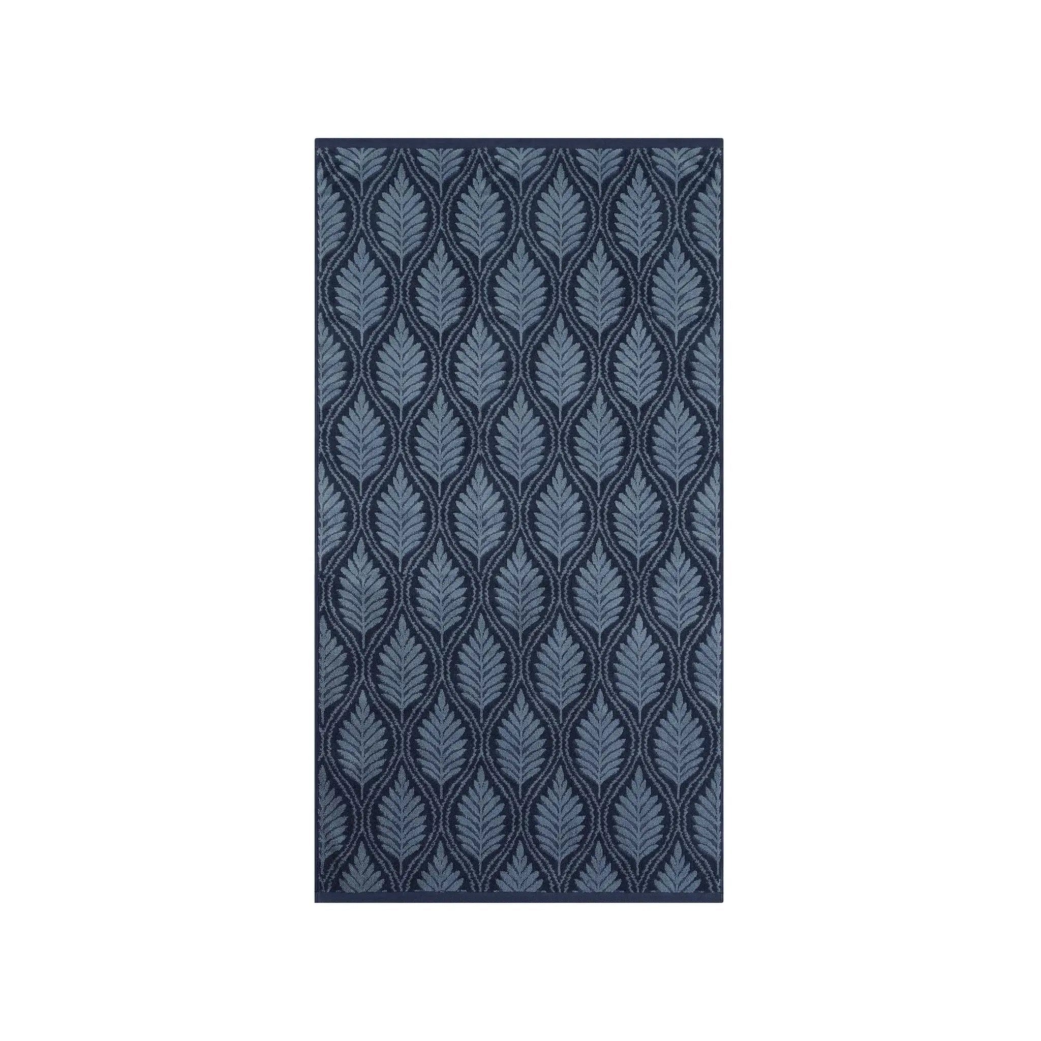 A navy bath towel with vertical pattern of stylized leaf or feather motifs in shades of blue and gray on a dark navy background, shown against a plain white background.