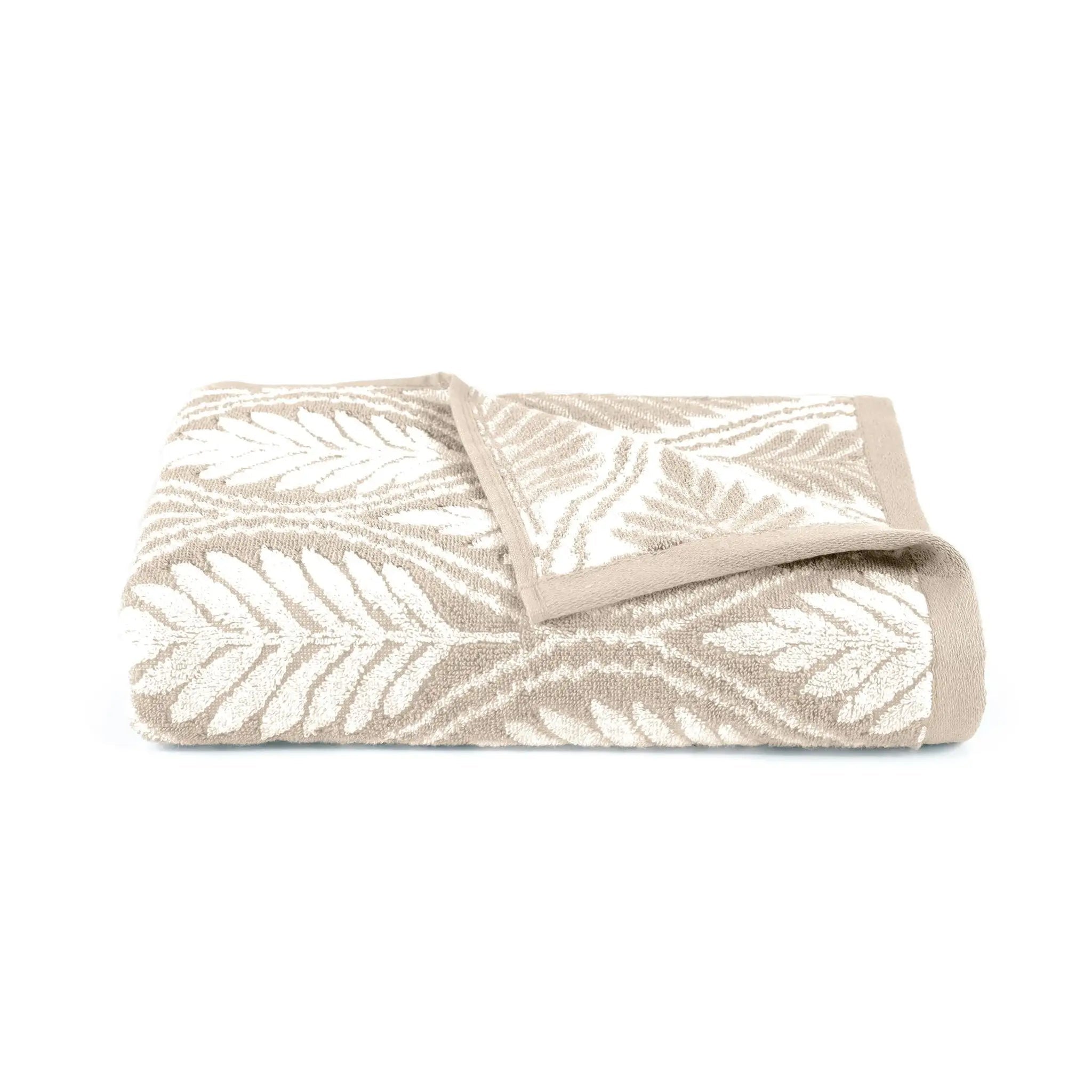 Folded sand colored bath towel with leaf pattern on a white background