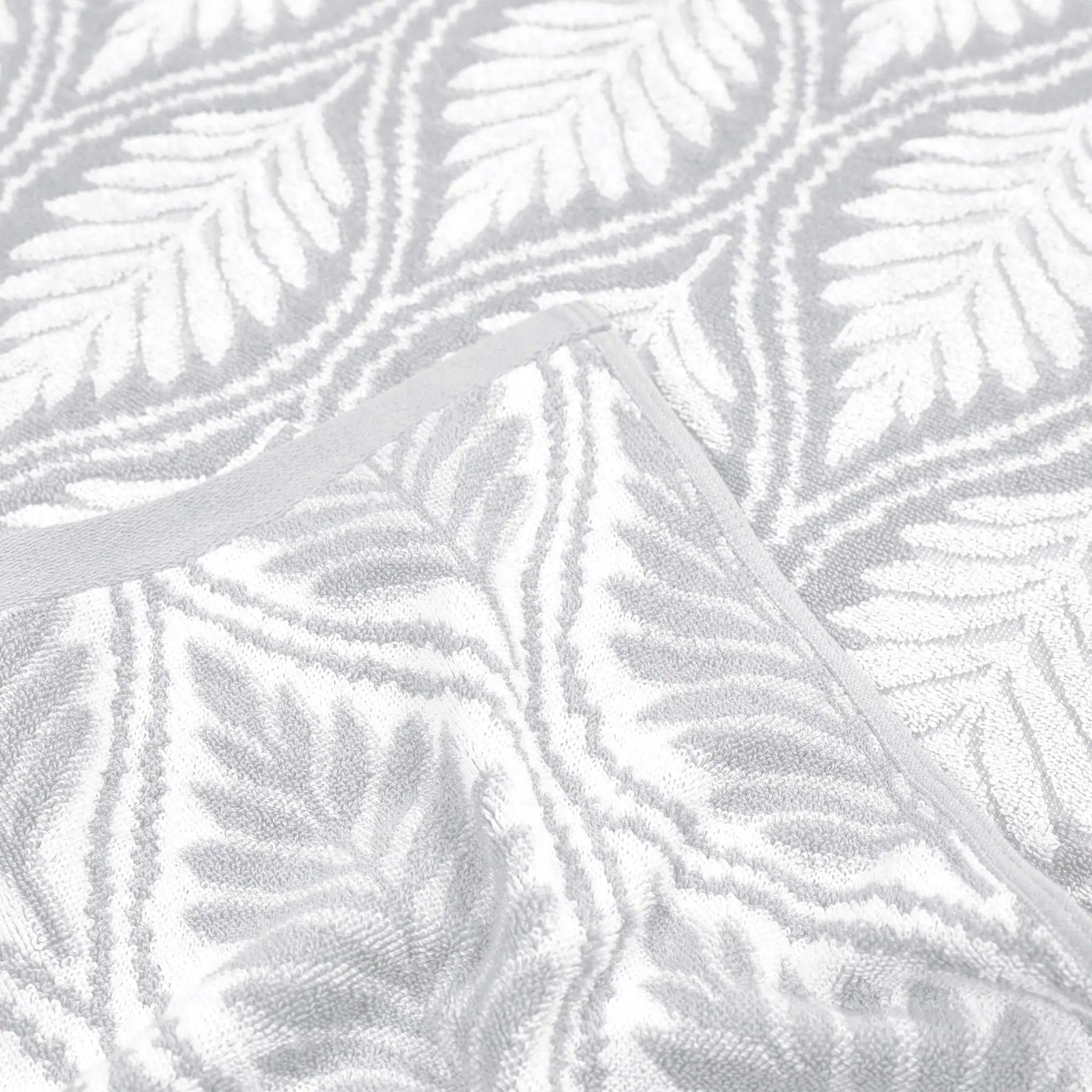 A close-up of a grey textured fabric with a raised gray leaf pattern and a matching gray trim.
