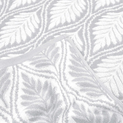 A close-up of a grey textured fabric with a raised gray leaf pattern and a matching gray trim.