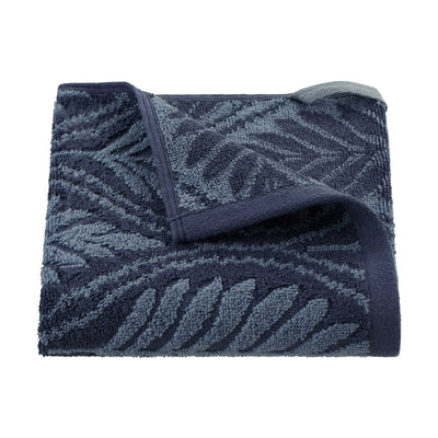 Folded navy towel with leaf pattern on a white background