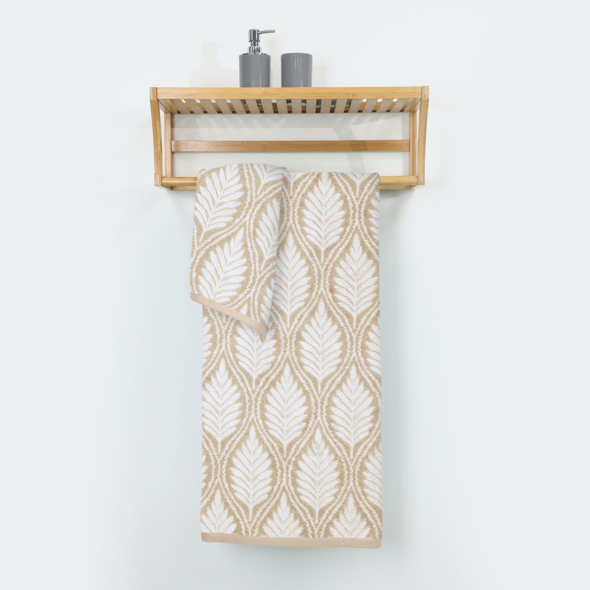 Folded sand towel with leaf pattern hanging on a wooden rack against a white background