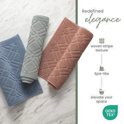 Three textured bath rugs in blue, gray, and clay on a marble surface with 'OEKO-TEX' certification.