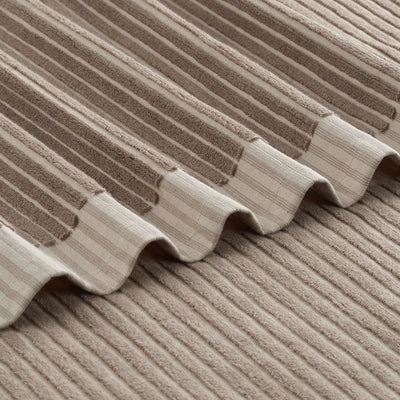 Close-up of a tan bath towel, showing the texture and wavy stitched edge.