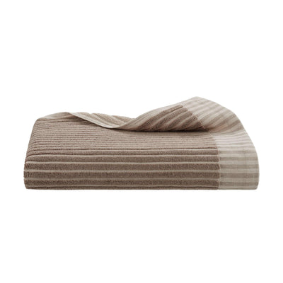 Folded tan bath towel on a white background