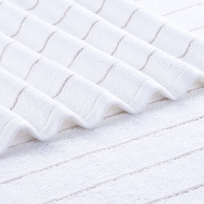 A close-up of a white textured fabric towel with a wavy, ribbed pattern and soft, plush loops.