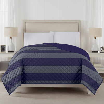 Bed with navy and gray striped coverlet in a bedroom setting