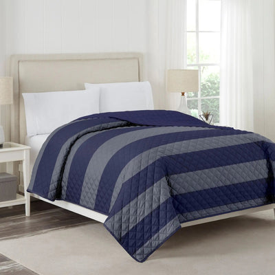 Bed with navy and gray striped coverlet in a bedroom setting