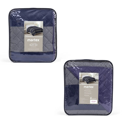 Two packaged Martex coverlet sets in a deep navy-blue color, shown on a clean white background. Each set is enclosed in clear plastic packaging with a gray quilted insert and a product label.