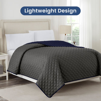 Graphite coverlet with navy reversible on a bed in a bedroom setting, labeled 'Lightweight Design'.