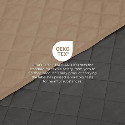 Quilted coverlet shown diagonally, Reversible in khaki and in graphite, with a central OEKO-TEX certification label and text about textile safety.