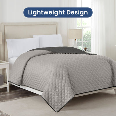 Light gray/graphite reversible coverlet on a bed with 'Lightweight Design' text above.
