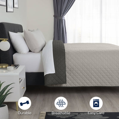 Bed with light gray/graphite coverlet in a bedroom setting.