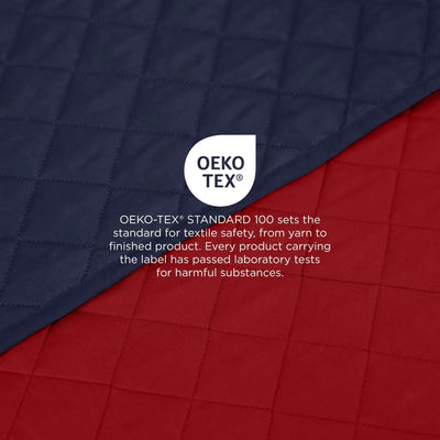 Two quilted coverlet shown diagonally across the frame, with a navy-blue panel on top and a red panel on the bottom. A white circular OEKO-TEX logo and explanatory text are overlaid in the center, emphasizing textile safety.