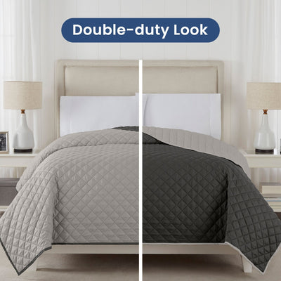 Two views of a light gray/graphite reversible coverlet draped over it, one in light gray and one in graphite, on a neutral background.