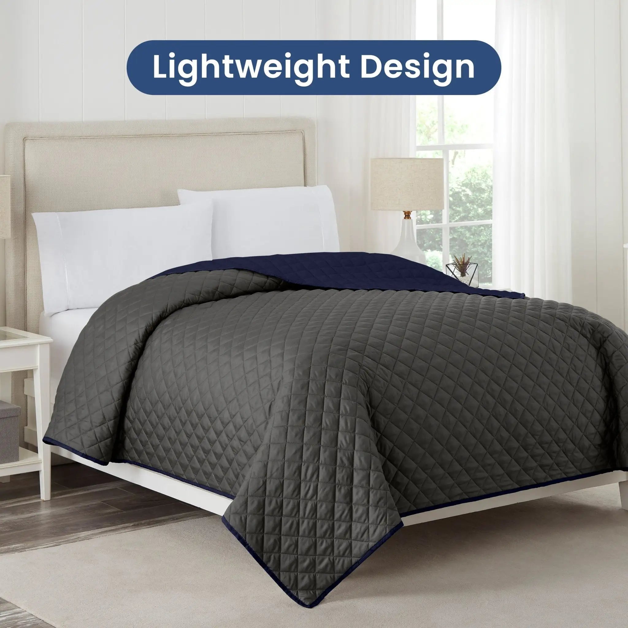 Gray coverlet with navy reversible on a bed in a bedroom setting, labeled 'Lightweight Design'.
