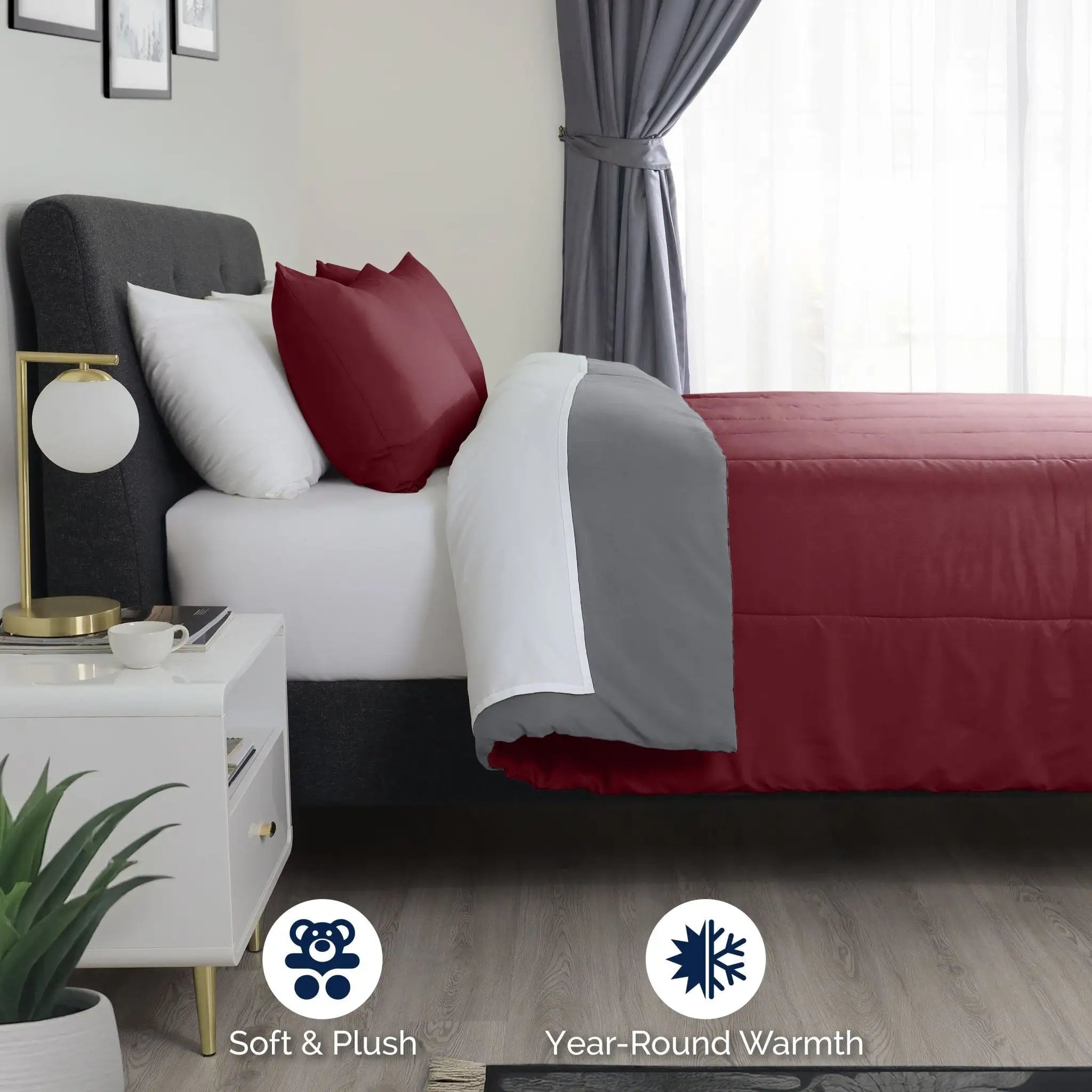 Bedroom with a bed covered in burgundy and gray reverse side comforter.