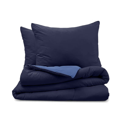 Navy blue bedding set with two pillow shams and a folded comforter on a white background