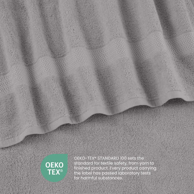 A close-up of a silver textured towel with a wavy patterned border, shown with an OEKO-TEX certification badge and text overlay at the bottom.