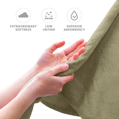 Sea green towel being held with hands, featuring icons and text about softness, linting, and absorbency.