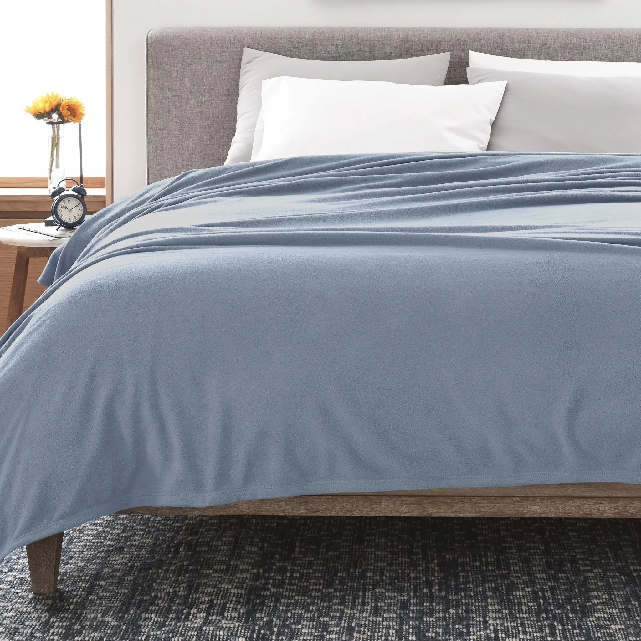 A light blue blanket neatly arranged on a bed in a modern bedroom setting.
