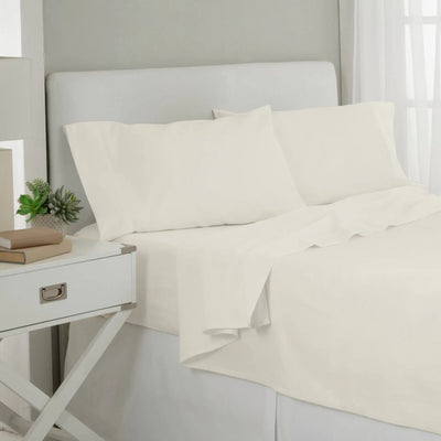 White cotton sheet and pillowcase set on a bed with a white upholstered headboard.