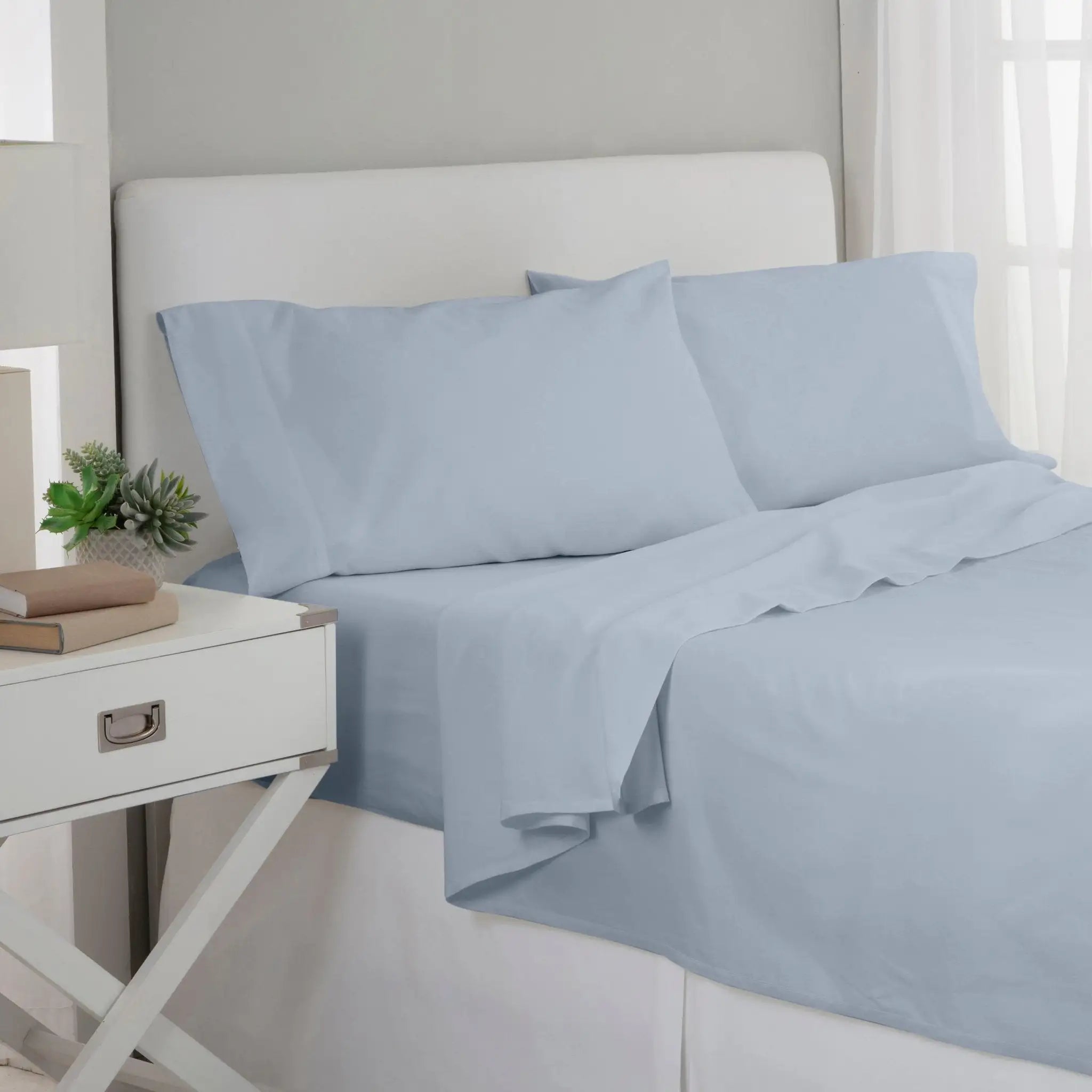 Blue bed sheets and pillows on a bed in a bedroom setting.