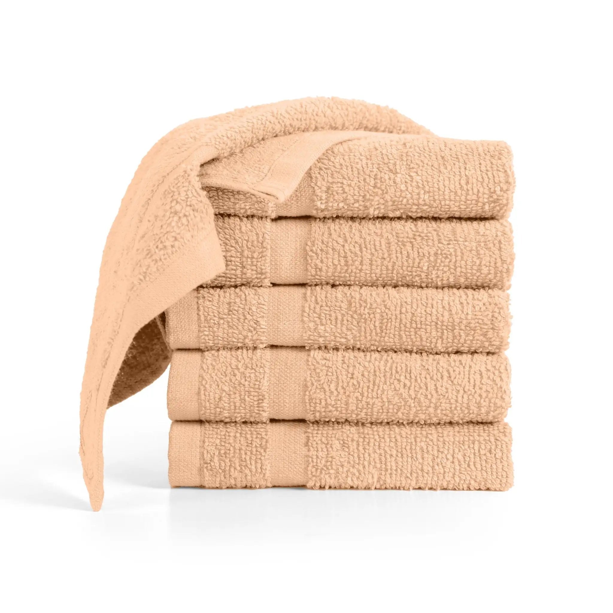 A stack of six folded peach color washcloths with a single washcloth draped over the top.