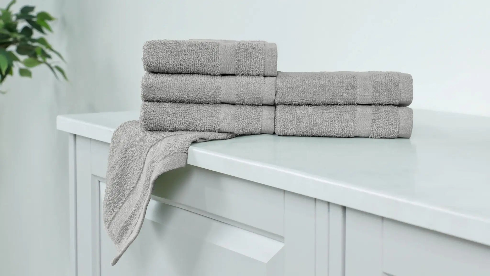 Stack of gray washcloths on a white cabinet.