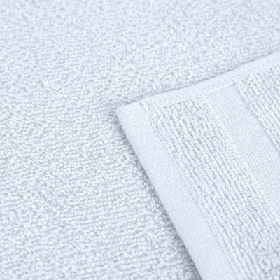 Close-up of a white textured washcloth with a folded corner showing its terry cloth weave and stitched border.