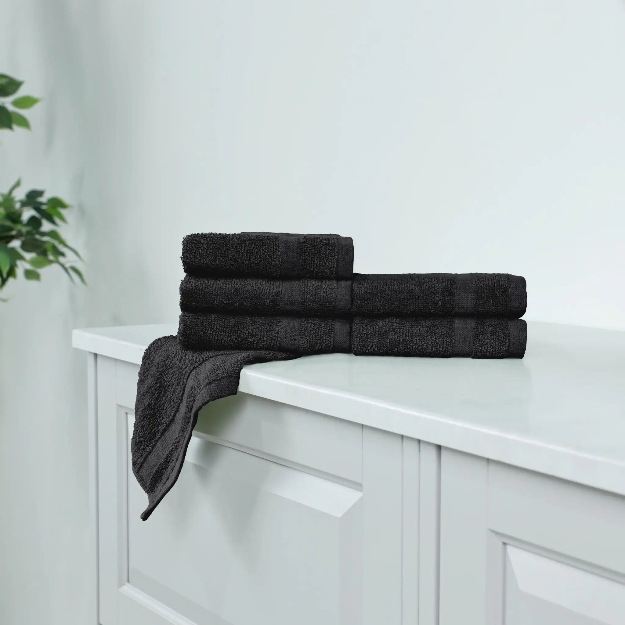Stack of black washcloths on a white cabinet.