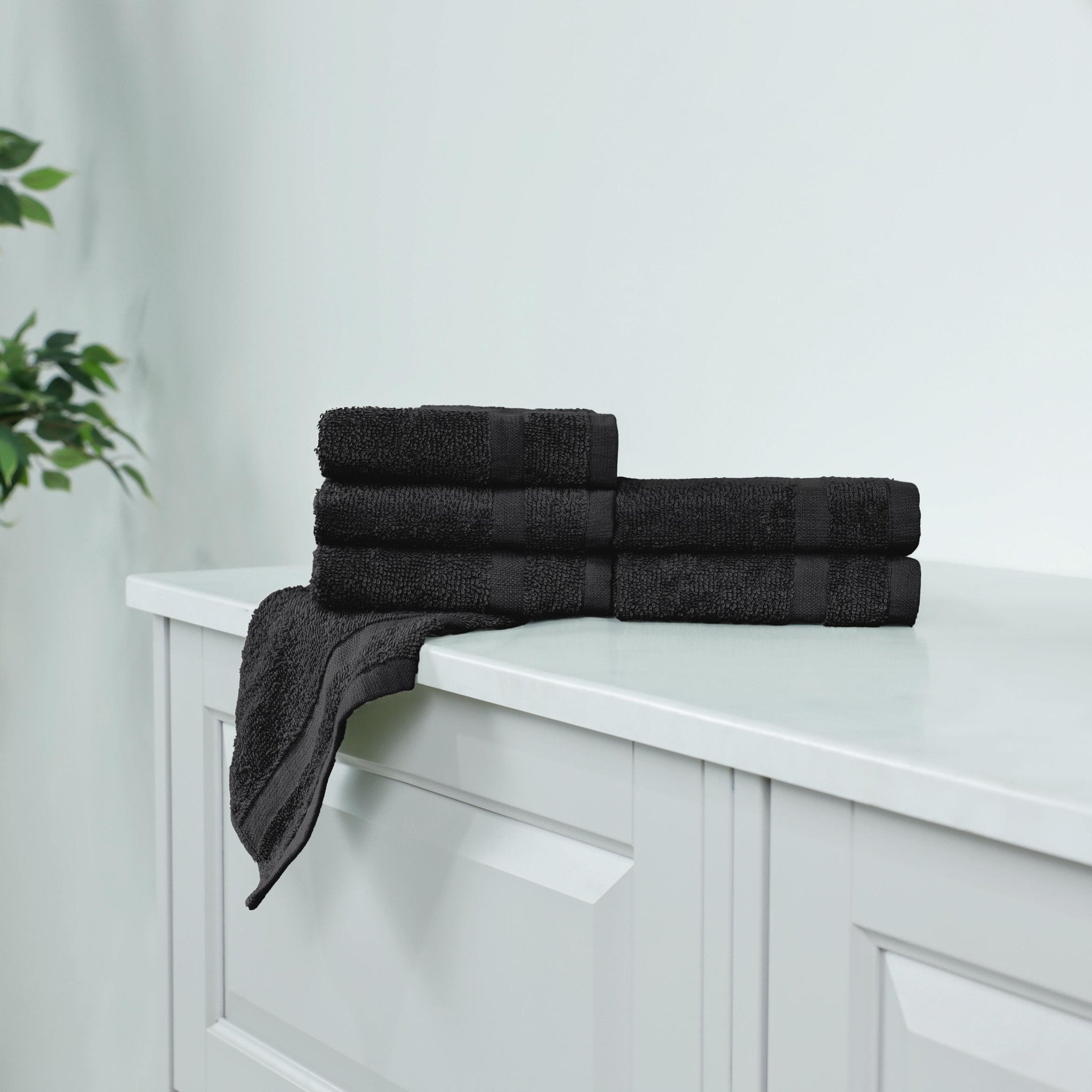 Stack of black washcloth on a white cabinet.