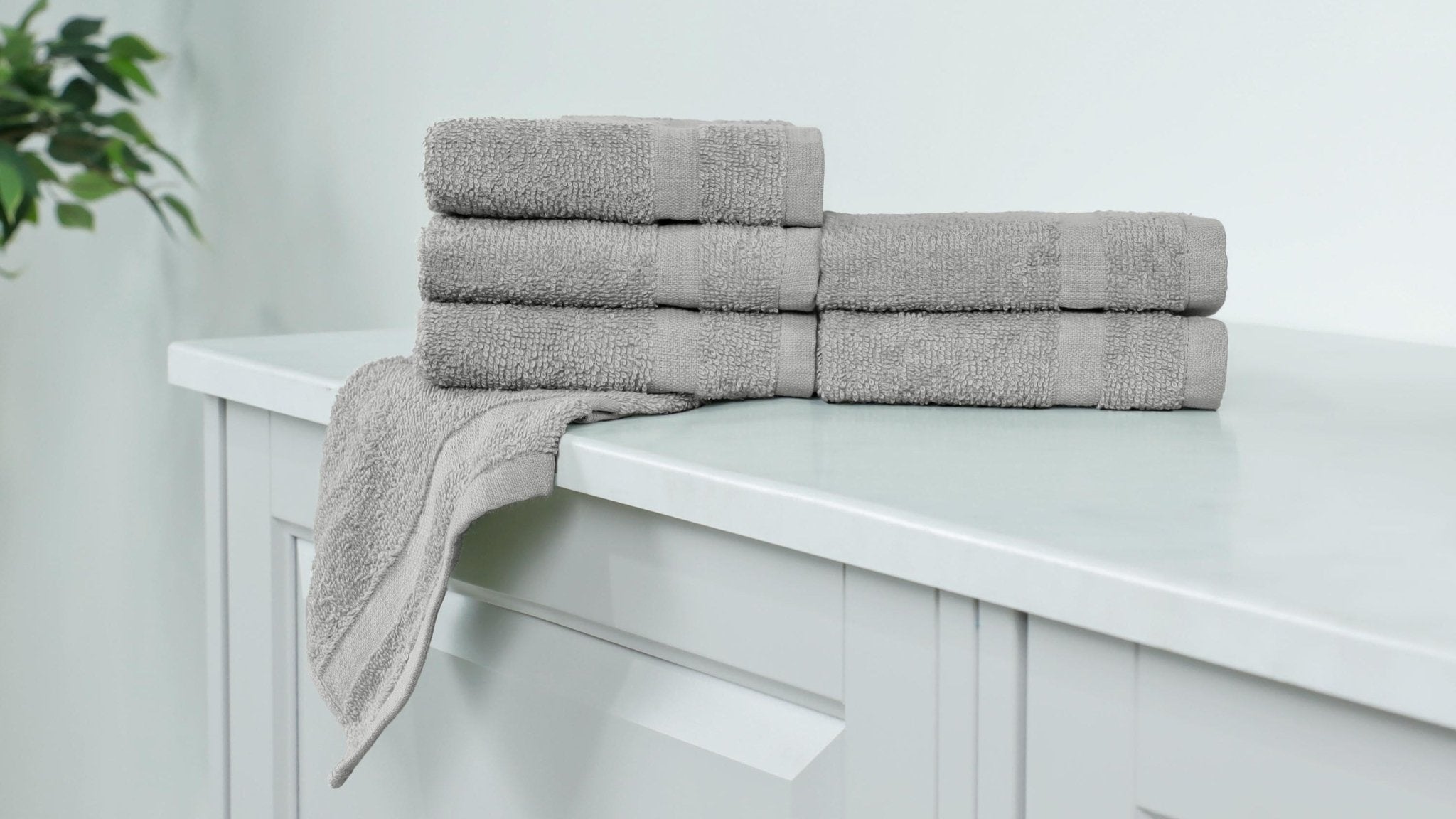 Stack of grey washcloth on a white cabinet.