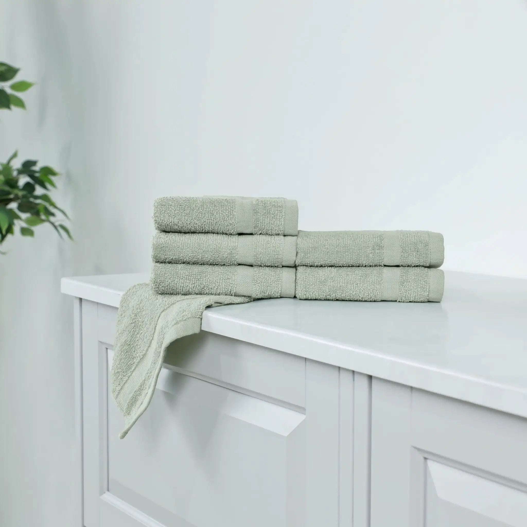 Stack of sage washcloths on a white cabinet.