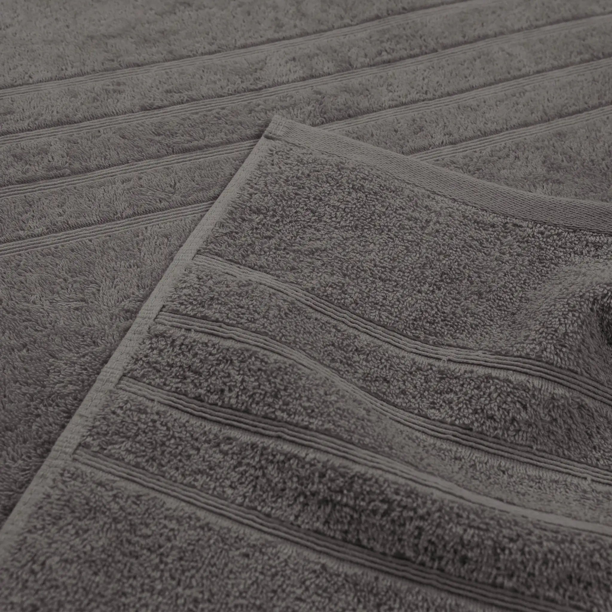 A close-up of a charcoal textured bath towel with horizontal ribbed stripes, showing its soft terry cloth texture.