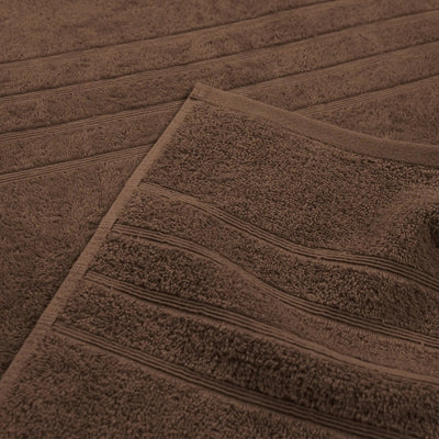 A close-up of a chocolate-colored bath towel with horizontal ribbed stripes, folded over to show its plush terry fabric.