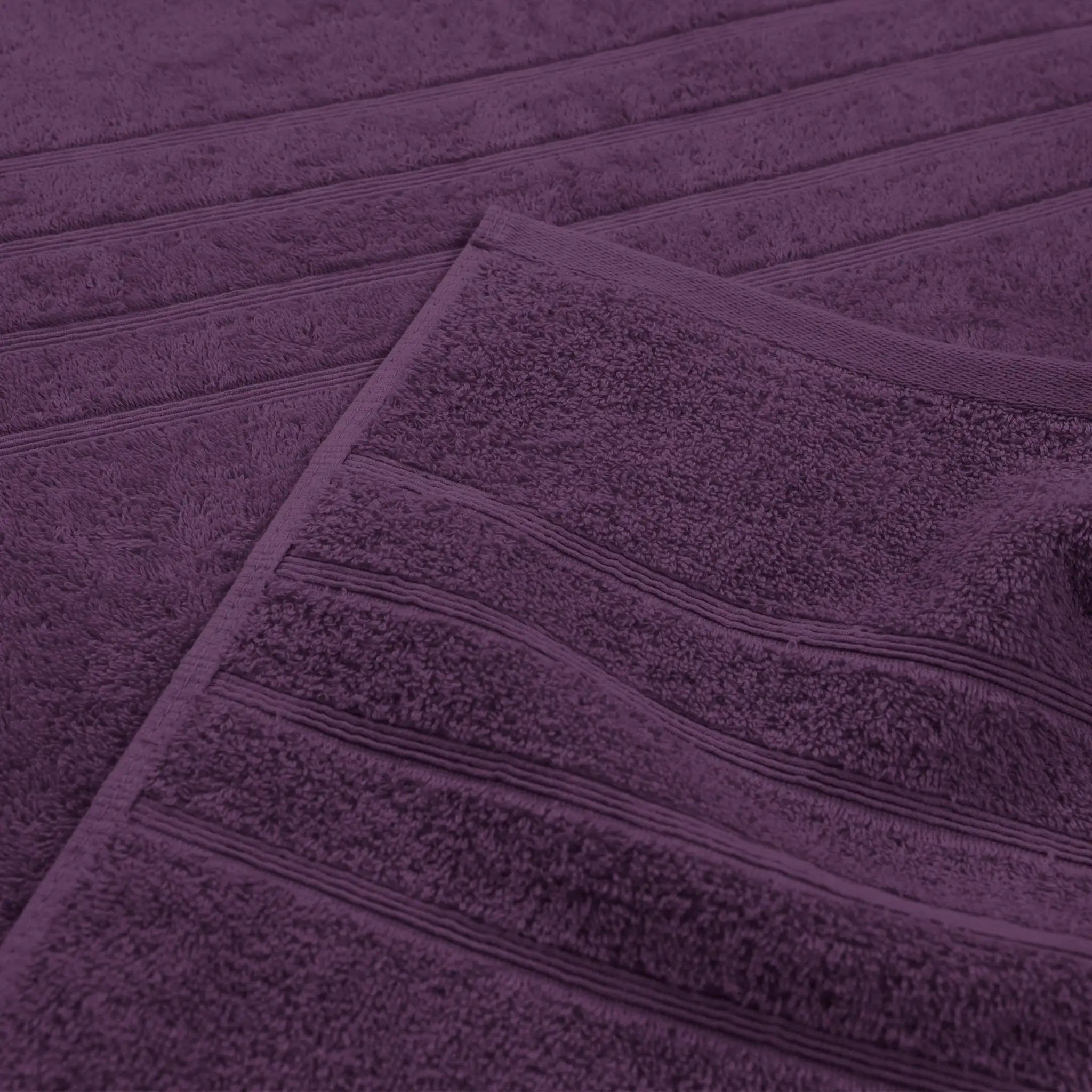 A close-up of a purple textured bath towel with horizontal ribbed detailing, folded diagonally.