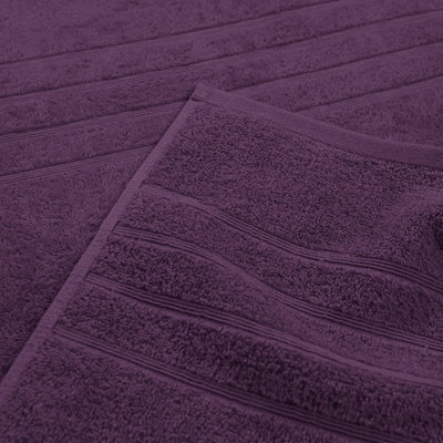 A close-up of a purple textured bath towel with horizontal ribbed detailing, folded diagonally.