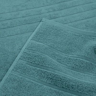 A close-up of a larkspur teal bath towel with horizontal ribbed stripes, folded over to show its soft texture.