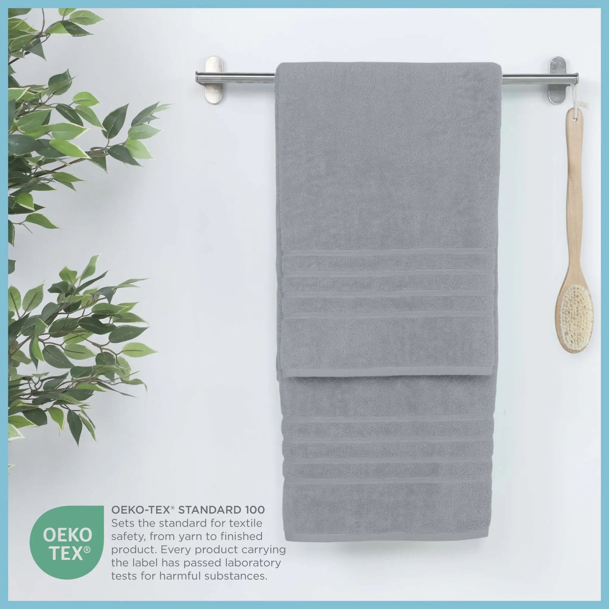 Spa blue bath sheet hanging on a rack with a plant and brush on a white background, featuring OEKO-TEX certification.