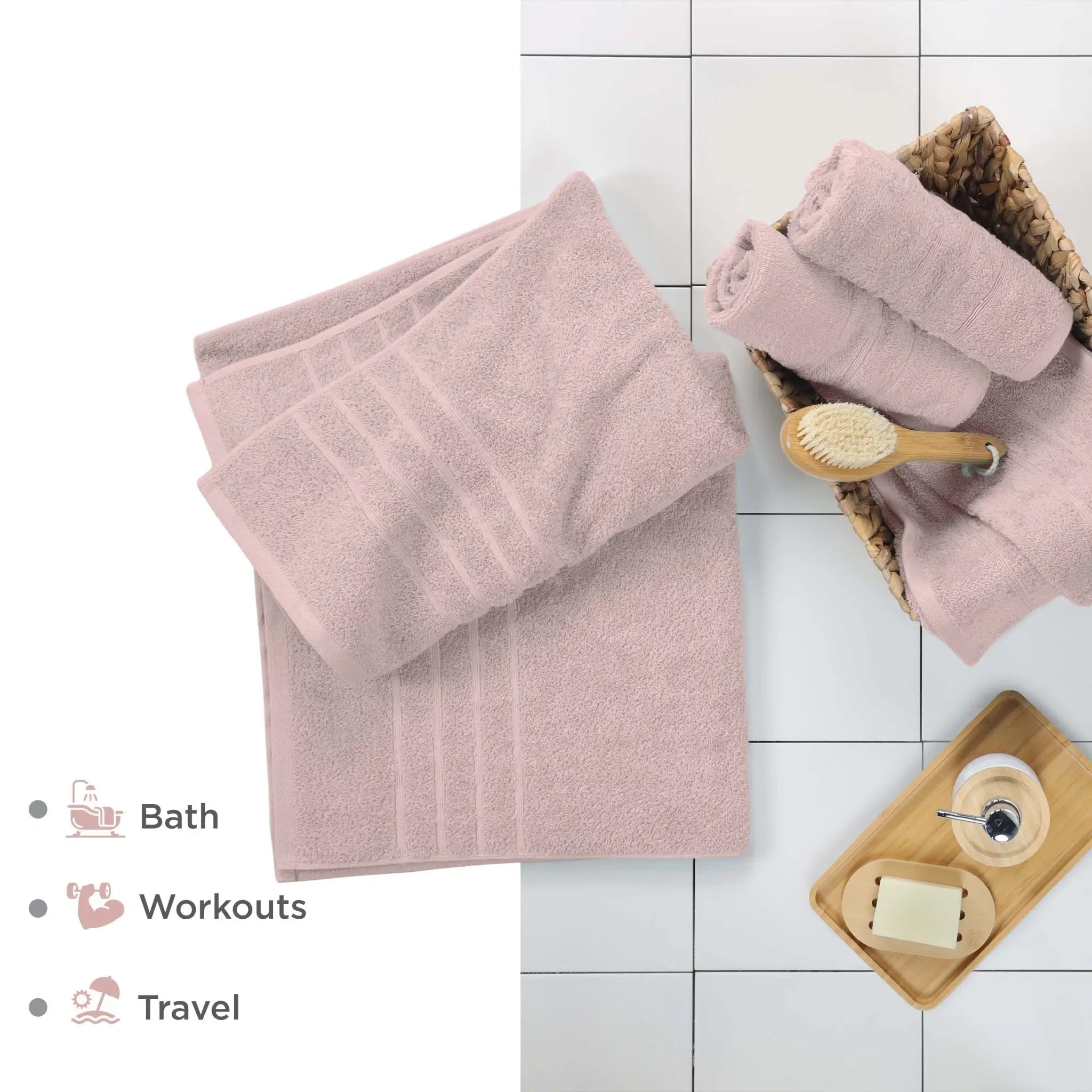 Pink bath sheets on a tiled floor with a brush and soap dish.