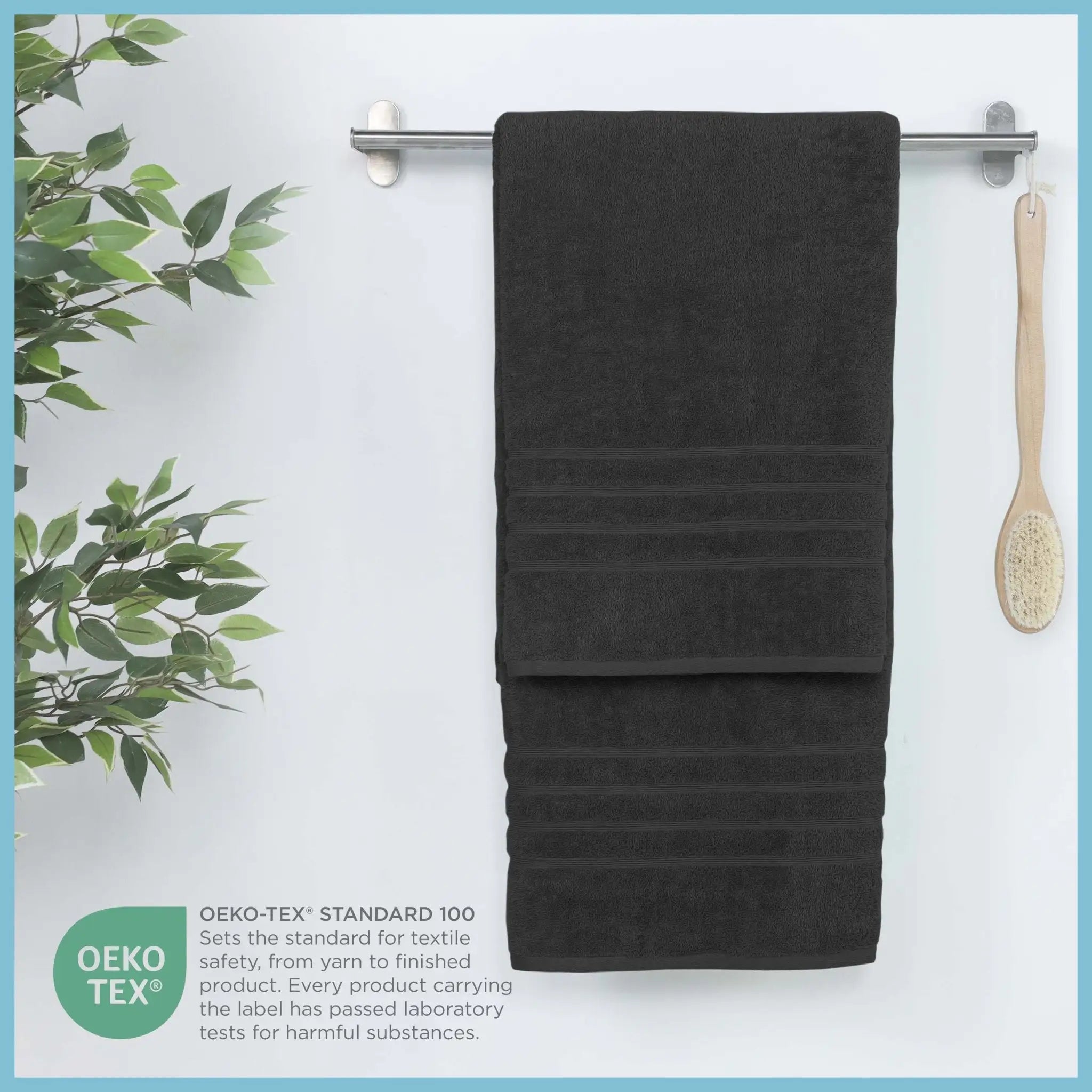Black bath sheet hanging on a rack with a plant and brush in the background, featuring OEKO-TEX certification.