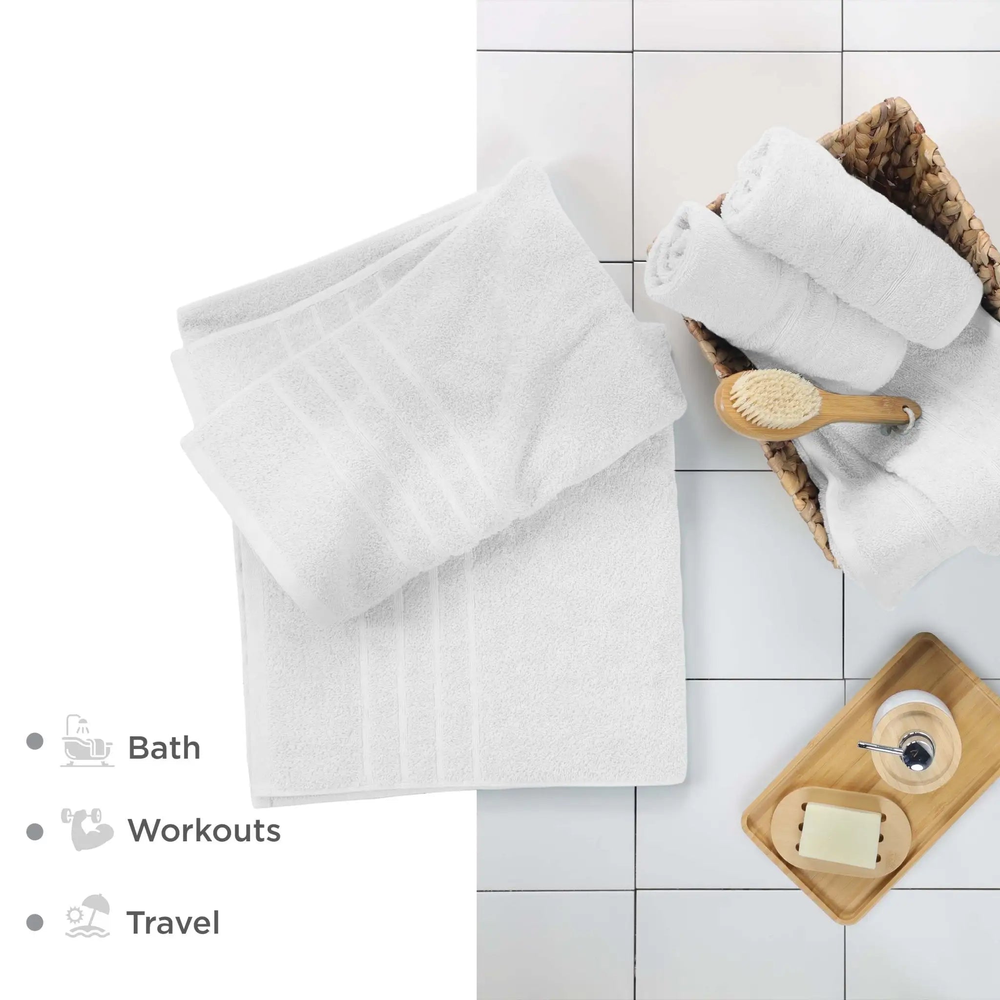 White bath sheets and bathroom accessories on a tiled floor