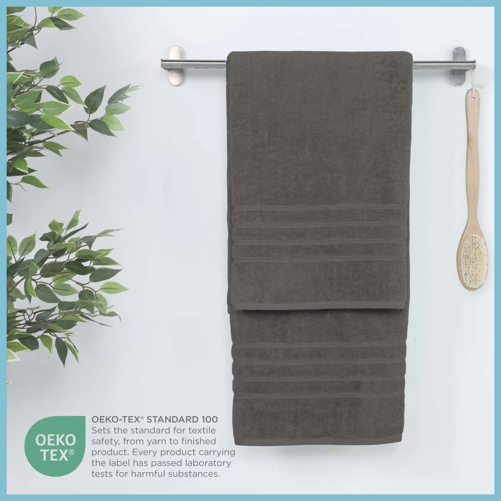 Gray bath sheet hanging on a rack with a plant and brush on a light blue background
