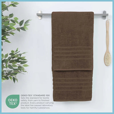 Chocolate colored bath sheet hanging on a rack with a plant and brush on a light blue background
