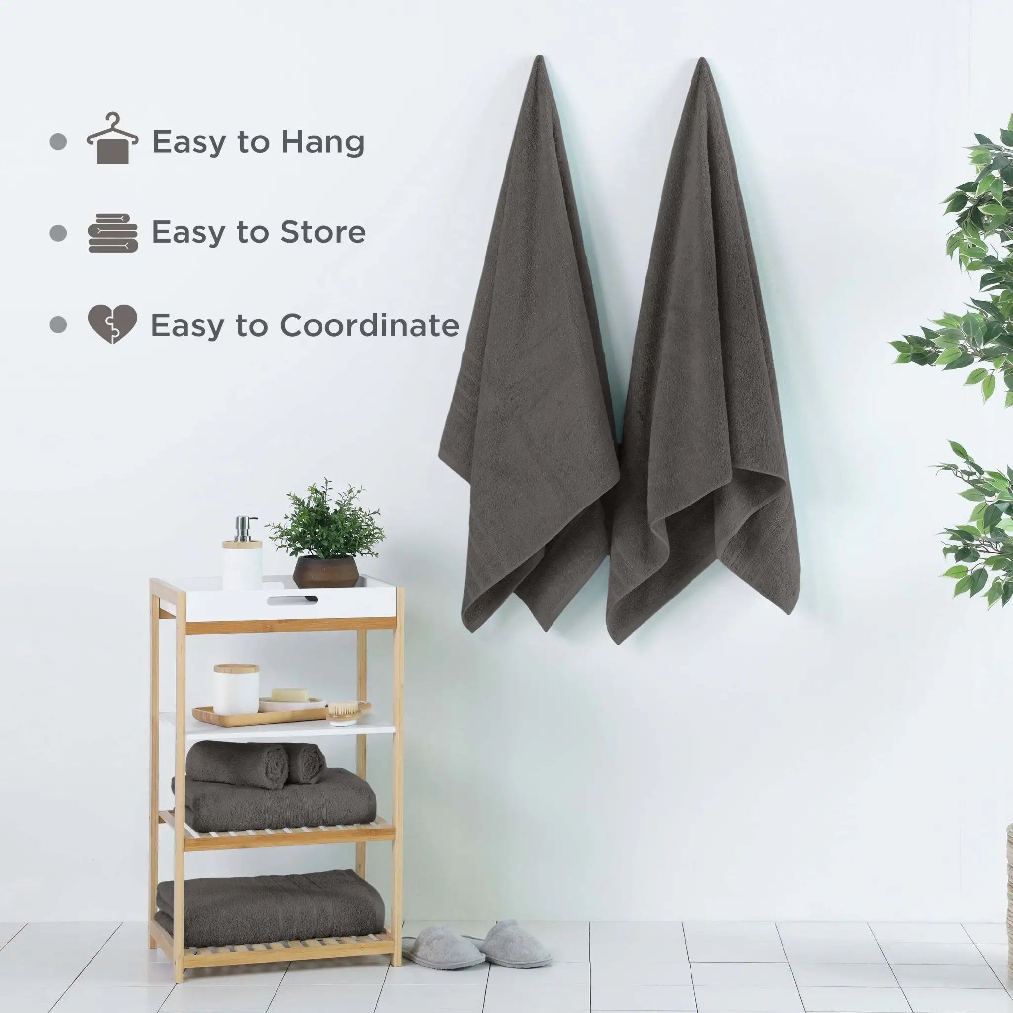 Dark grey bath sheets hanging on a wall with a wooden shelf below, featuring text about towel features.