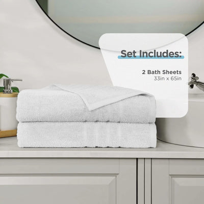 Two folded white bath sheets stacked on a bathroom counter, with a white informational overlay that reads 'Set Includes: 2 Bath Sheets 33in x 65in.' A sink, mirror, soap dispenser, and cabinet are visible in the background.