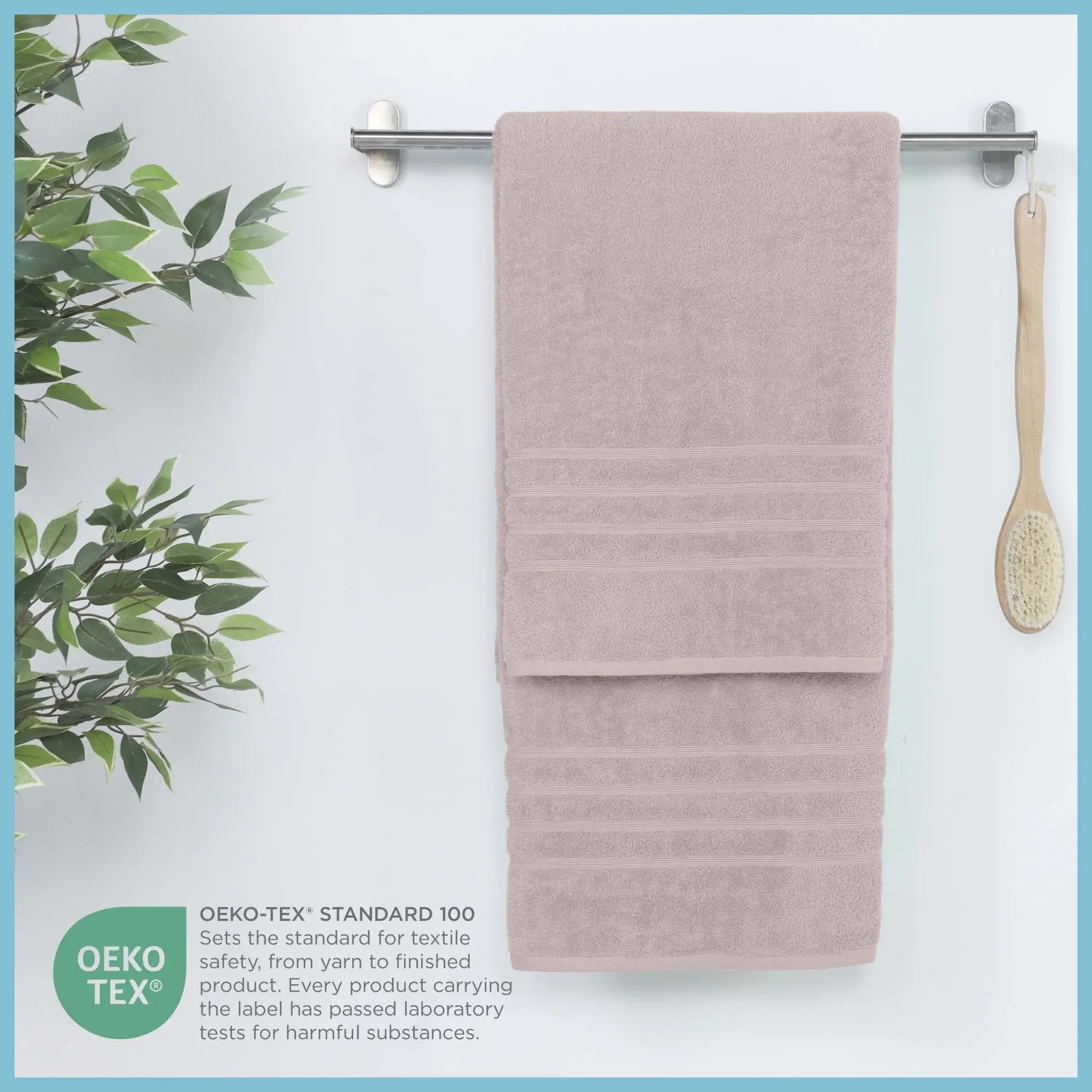 Folded pink bath sheets on a rack with a plant and brush, featuring OEKO-TEX certification.