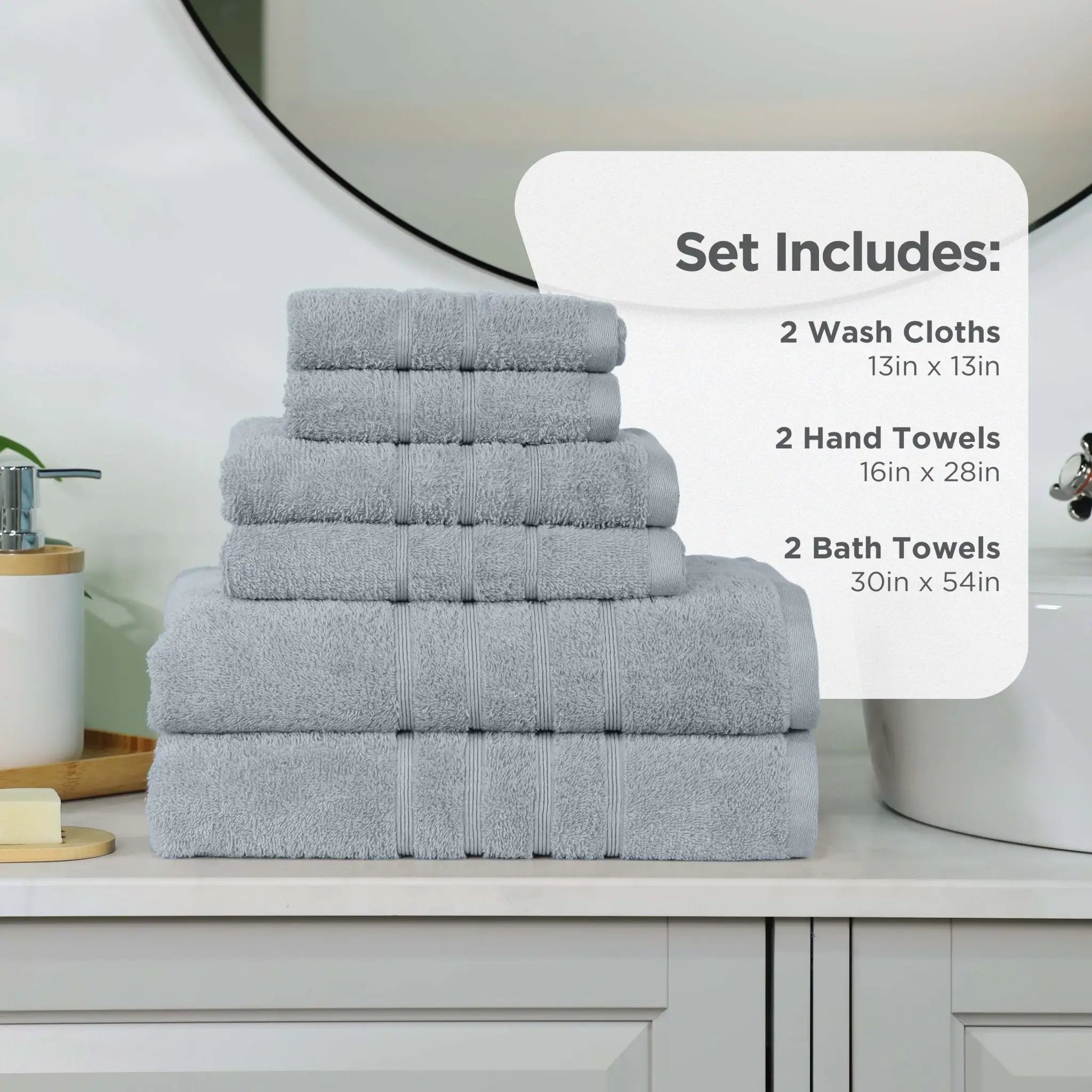 A stack of spa blue towel set displayed on a bathroom counter, with an informational overlay detailing the set contents: 2 wash cloths 13in x 13in, 2 hand towels 16in x 28in, and 2 bath towels 30in x 54in.
