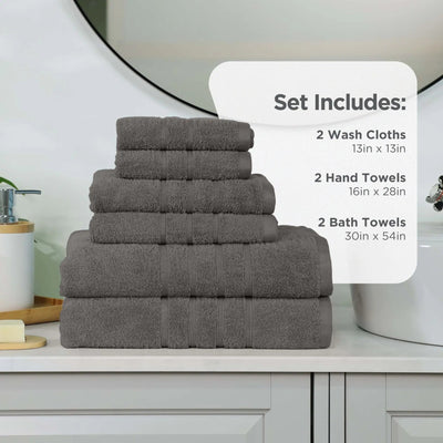 A stack of dark gray towel set displayed on a bathroom counter, with an informational overlay that reads 'Set Includes: 2 Wash Cloths 13in x 13in, 2 Hand Towels 16in x 28in, 2 Bath Towels 30in x 54in'.